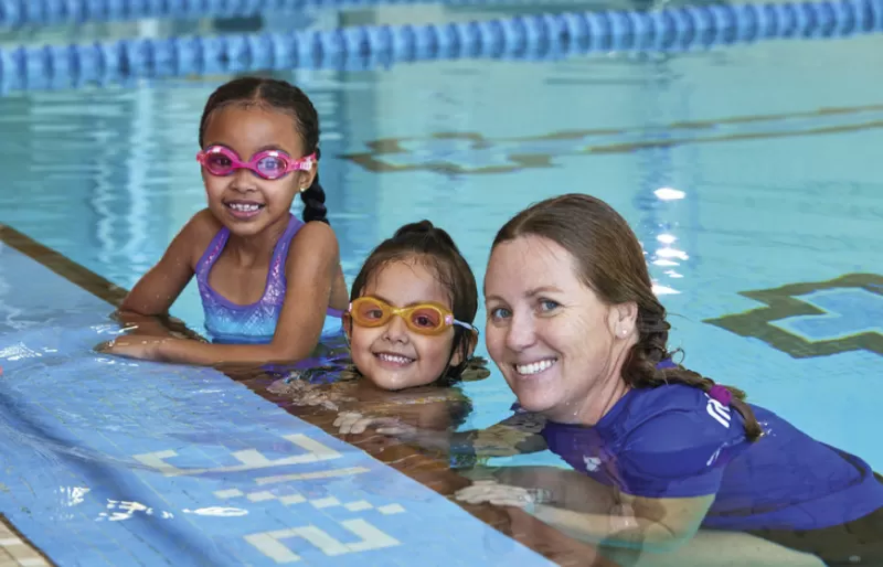 Children learning how to swim with YMCA instructor.