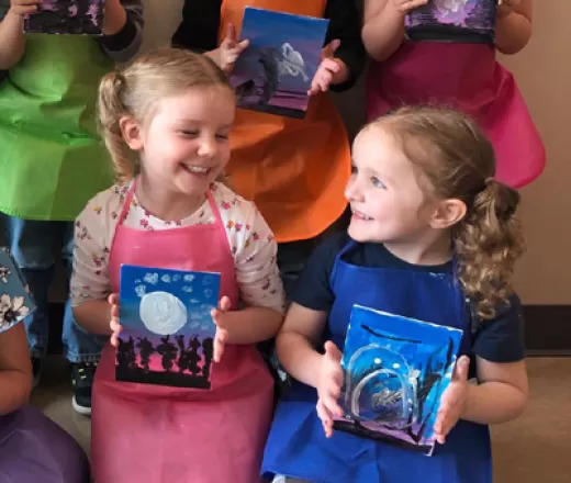 Two little girls holding their art they just painted.