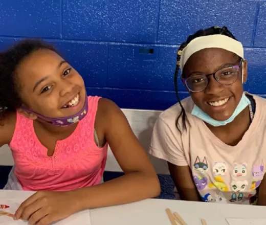 Two girls smiling while they do arts and crafts at the Y