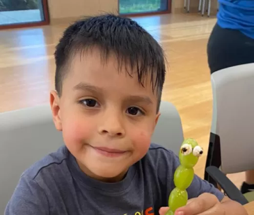 Child holding a caterpillar made of grapes
