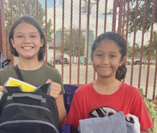 Two girls receiving backpacks at the Y's Back to School Event