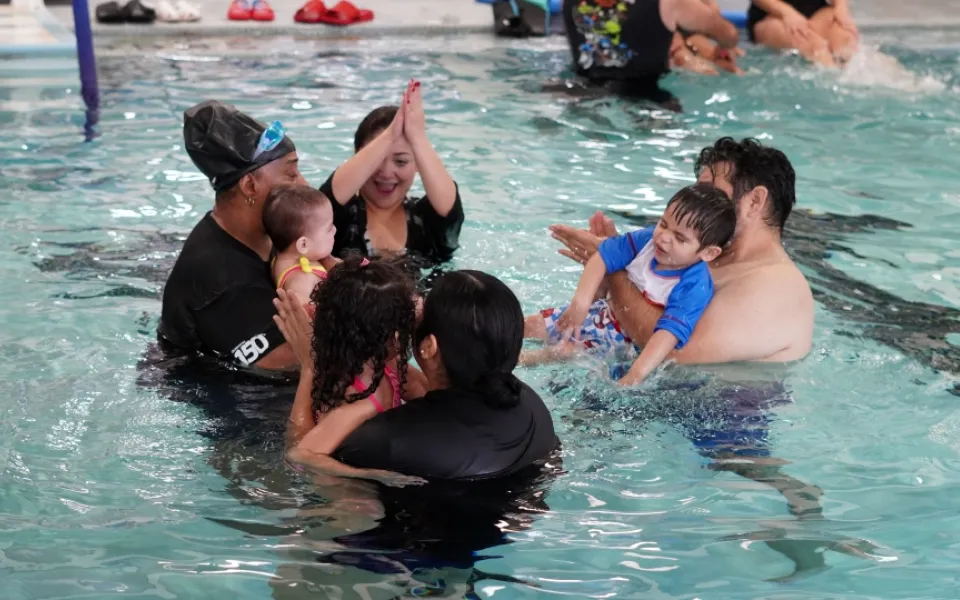 Parents along with a Y Swim Instructors teaching young children how to swim